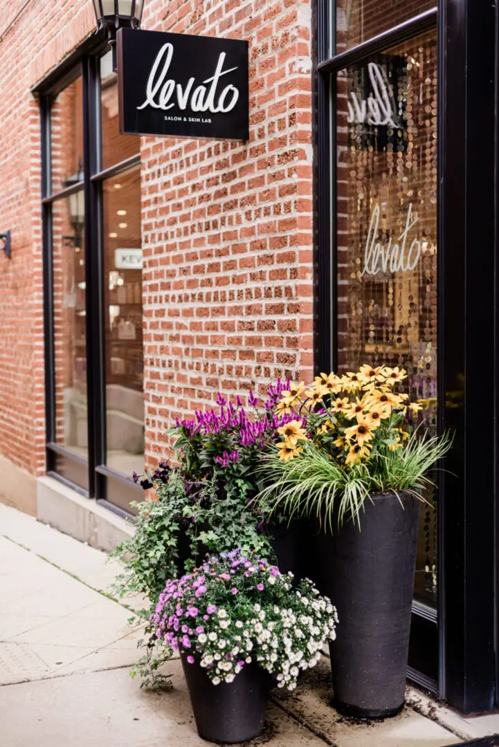 Flower pots outside brick storefront entrance.